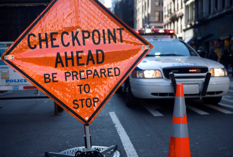 Image is of a an orange street sign that reads 'Checkpoint Ahead, Be prepared to stop', concept of what to expect at DUI checkpoints