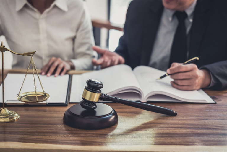 Image is of a lawyer sitting at a table with their client while going over paperwork, concept of questions to ask a DUI lawyer