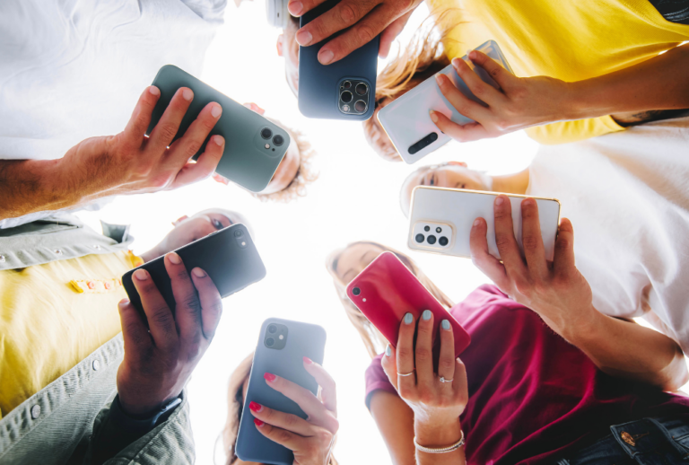 Image is of a group of teens looking down at their phones, concept of teen sexting laws in Florida