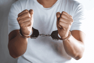 Image is of a man with his hands in cuffs, concept of identity theft charges in Ponte Vedra Beach