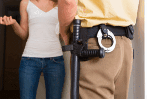 Image is of a close up of a police officer standing at the front door of a home and speaking to a woman who lives there, concept of your rights during a "knock and talk" in Ponte Vedra Beach