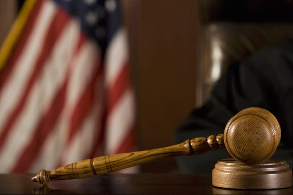 Wooden gavel on desk with American flag in background symbolizing justice