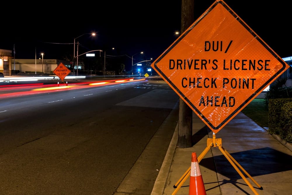 DUI checkpoint sign at night showing how a DUI affects your insurance rates.