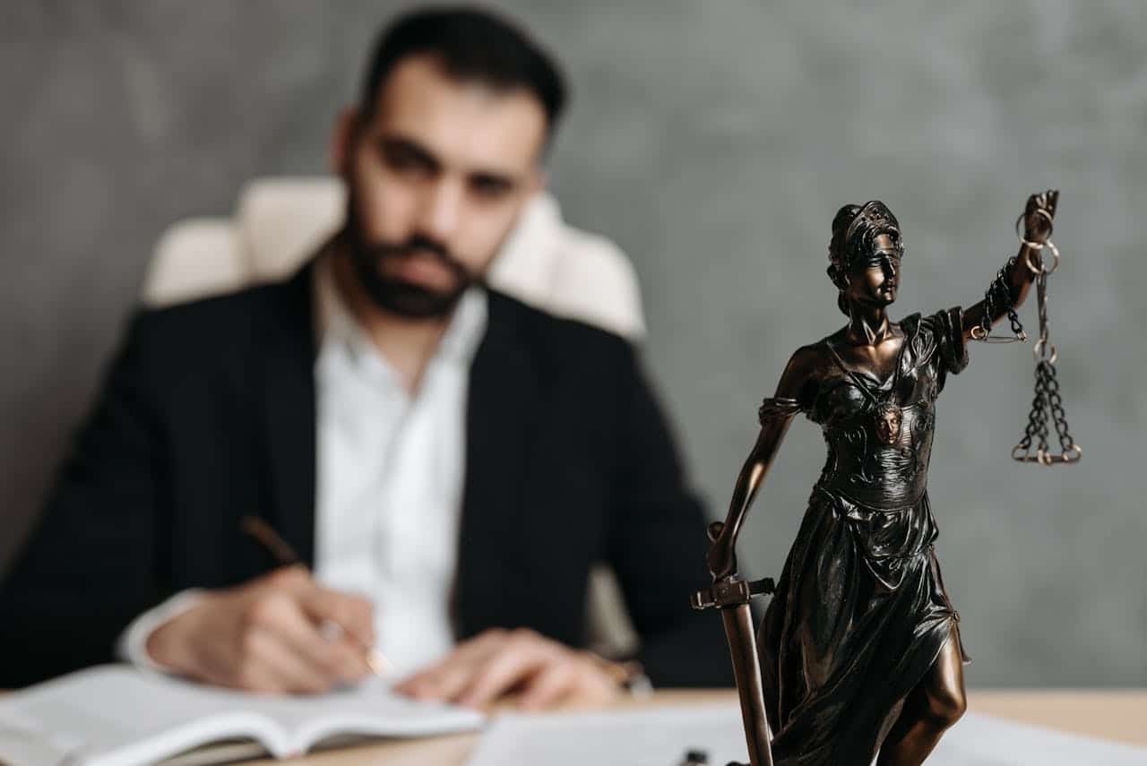 Defense lawyer working at desk with Lady Justice statue.