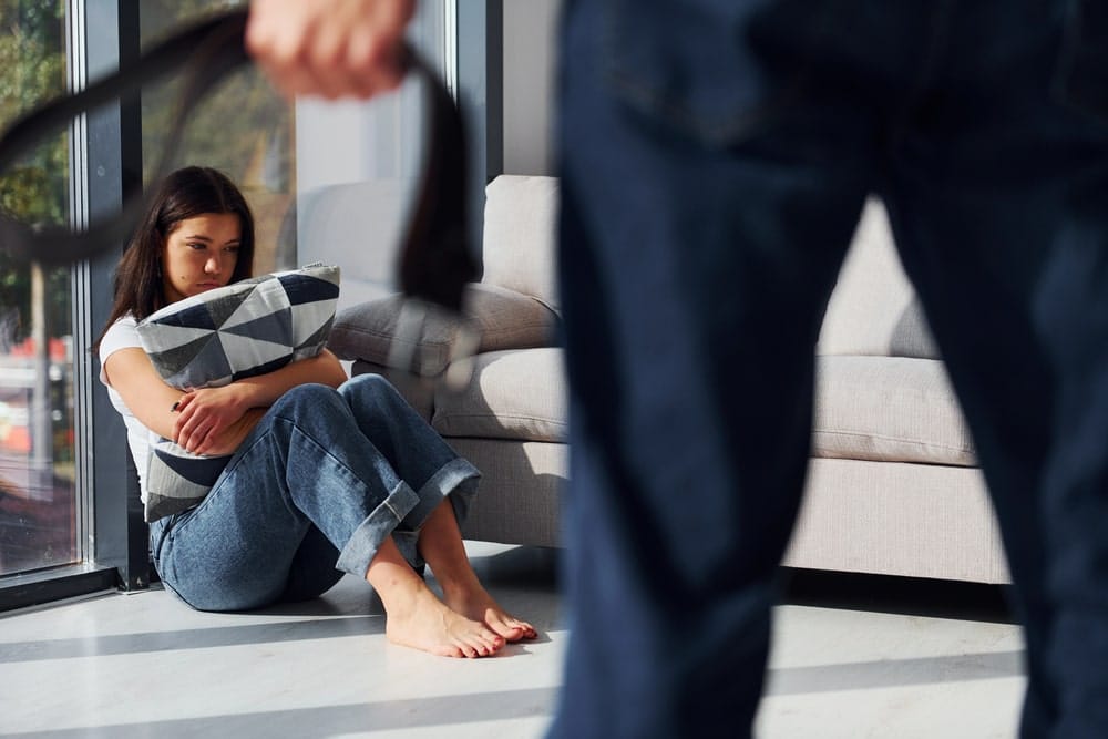 Woman sitting on the floor showing fear in a domestic violence situation.