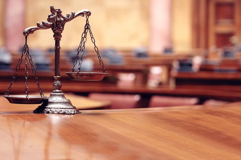 Image is of scales of justice placed inside a courtroom, representing how courts evaluate domestic violence charges and legal outcomes in Florida