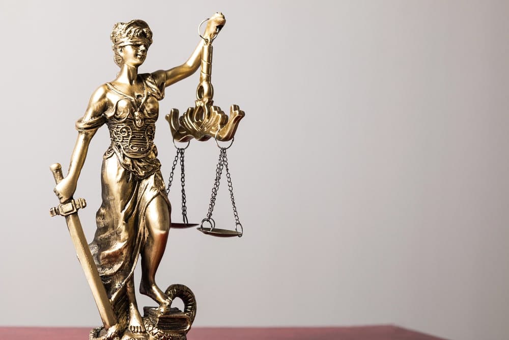 Image is of a Lady Justice statue holding scales and a sword, representing legal fairness in domestic violence cases.