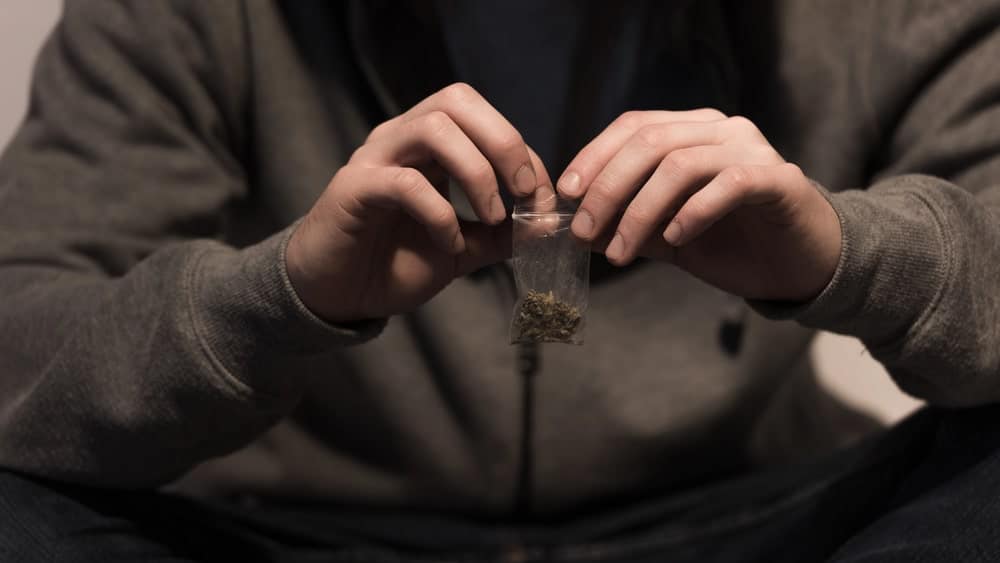 Image is of an individual holding a small bag of drugs, highlighting how Florida drug convictions can create long term immigration risks beyond criminal court penalties.