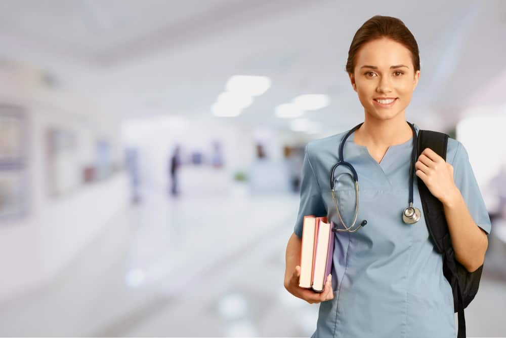 Image is of a healthcare professional holding books in a hospital hallway, concept of DUI impact on medical and professional licenses.