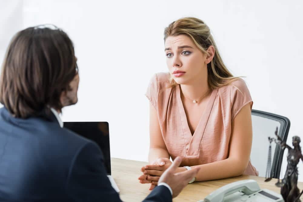 Image is of a woman consulting with a lawyer at a desk, discussing diversion program options for Florida domestic violence cases