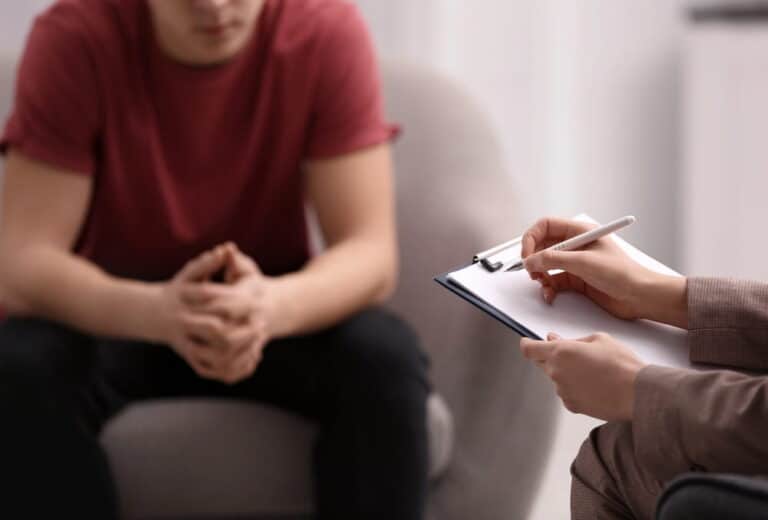 Image is of a counselor taking notes during a client session, reflecting counseling requirements in a diversion program for domestic violence cases