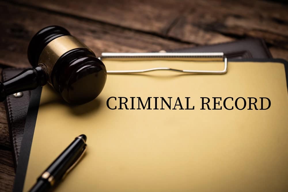 Image is of a folder labeled criminal record with a gavel and pen on a desk, concept of how a DUI conviction appears and remains on a Florida criminal record.