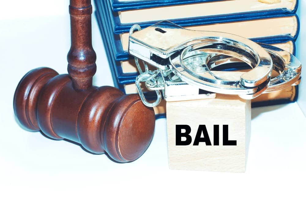 Image is of a judge’s gavel, handcuffs, and a bail block on legal books, concept of court process after a drug arrest in Florida.