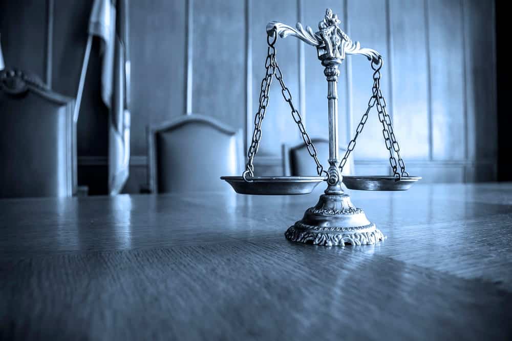 Image is of scales of justice in a courtroom setting, concept of DUI charge and legal balance in court decisions