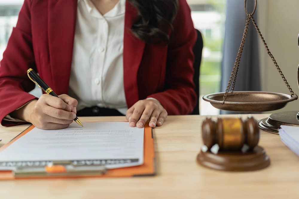 Image is of a lawyer signing legal documents beside a gavel, representing legal defense strategies in cases involving false DV allegations.