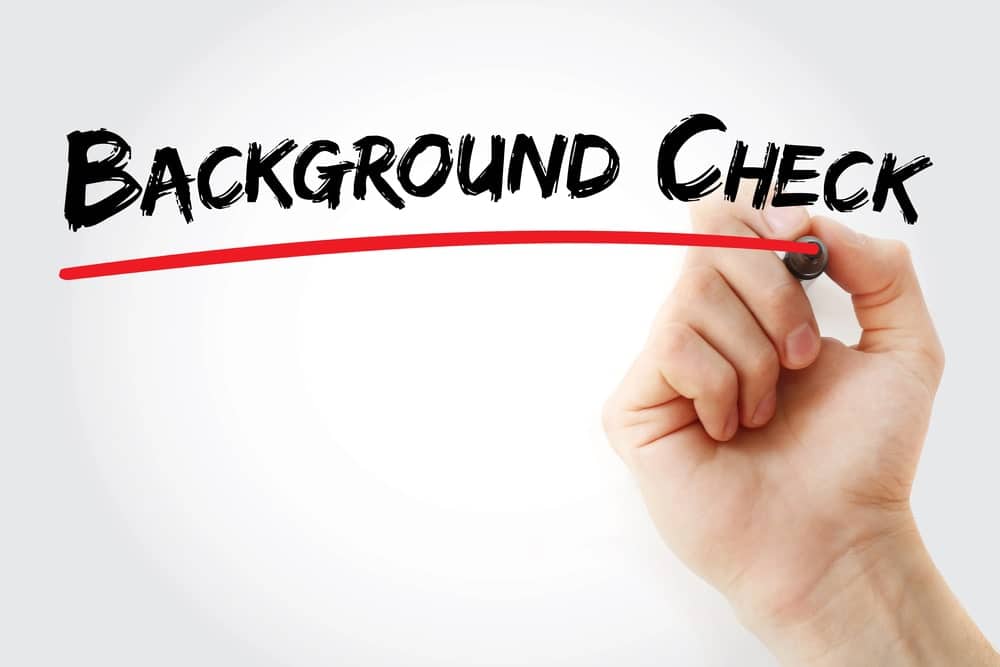 Image is of a hand writing background check text, concept of drug charges appearing in screening records