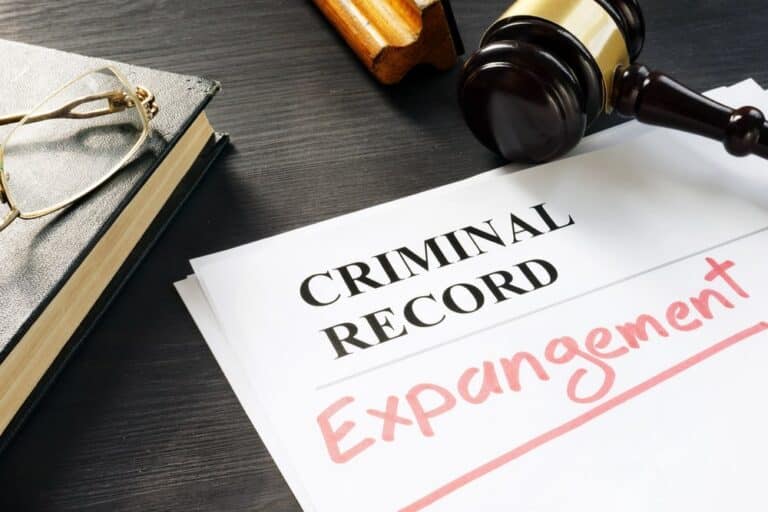 Image is of criminal record expungement paperwork beside a judge’s gavel, concept of removing a past drug charge from public records.
