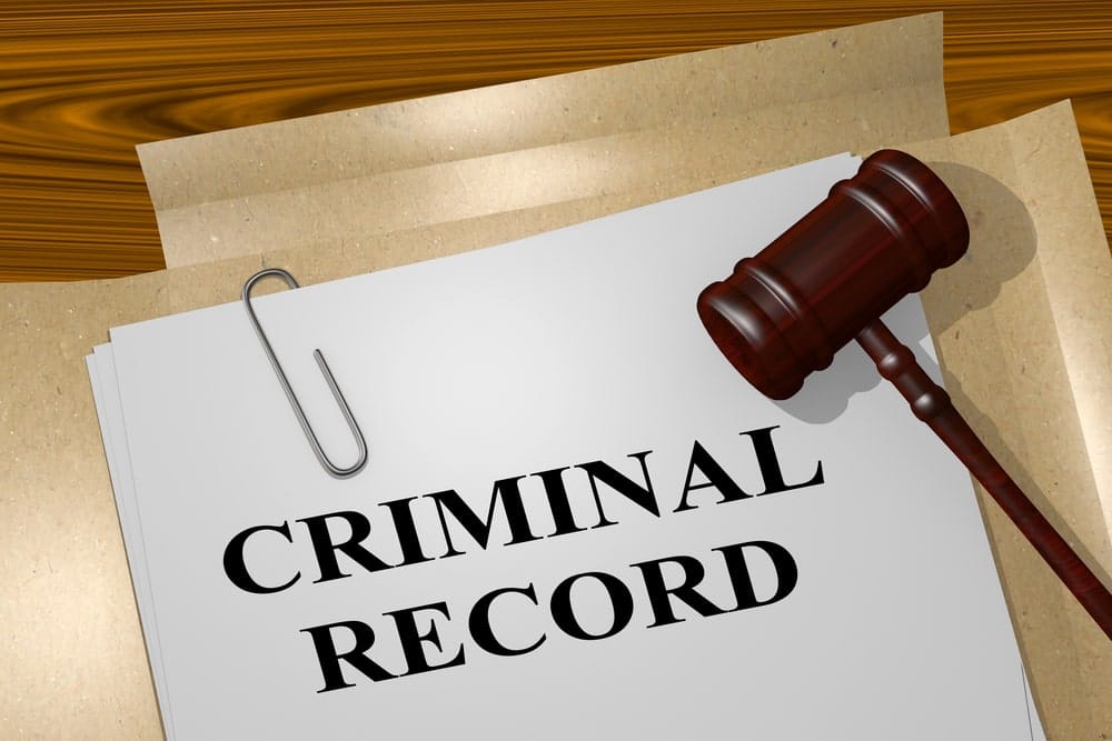 Image is of a criminal record file with legal documents and a courtroom gavel, concept of reviewing eligibility to expunge a drug charge.