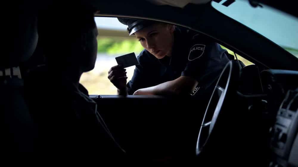 Image is of a police officer checking a driver’s license during a traffic stop, concept of Ponte Vedra Beach DUI cases.