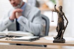 Image is of a Lady Justice statue in a law office with an attorney reviewing case documents, concept of legal defense strategies for a DUI charge.