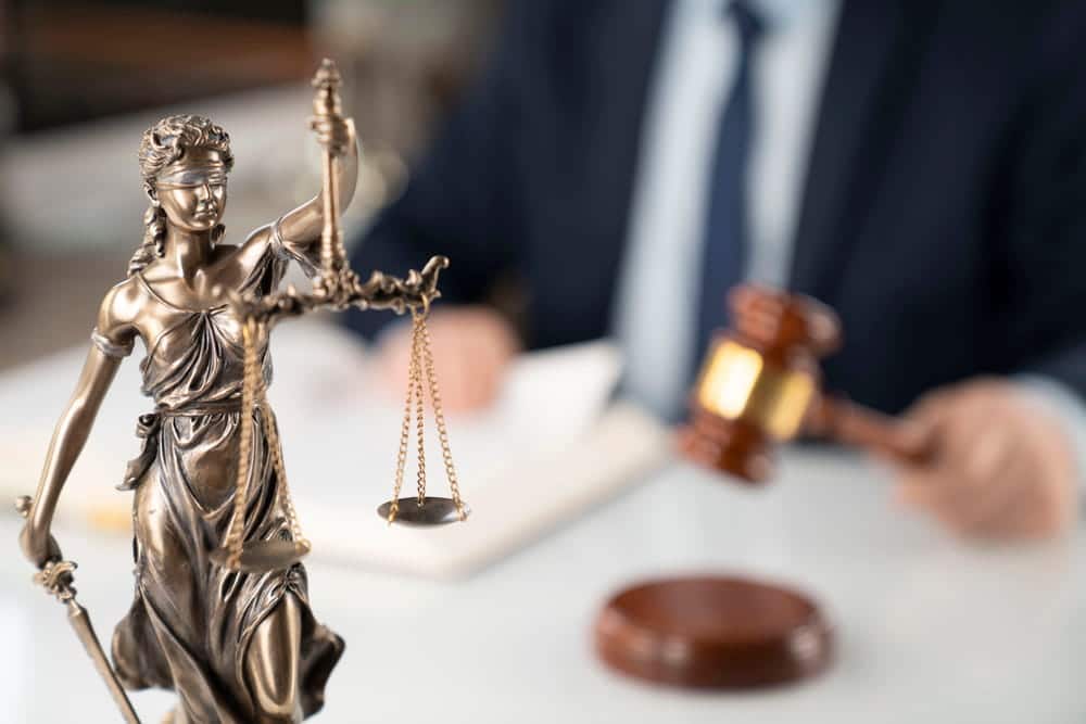 Image is of a Lady Justice statue and courtroom setting representing legal proceedings associated with a DV bond hearing.