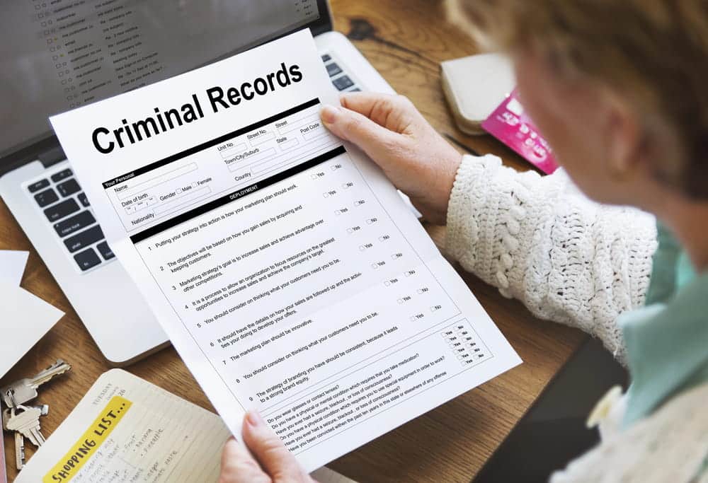 Image is of a person reviewing a criminal records document, concept of how a DV charge may appear during a background check.
