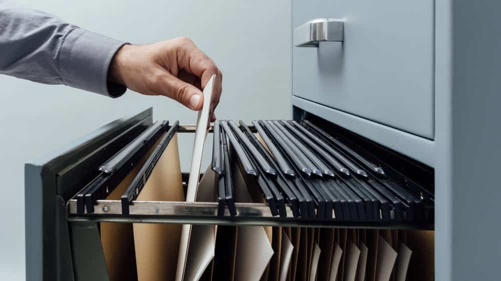 Image is of a person retrieving a file from a filing cabinet, concept of how a DV charge is stored and retained in official records.