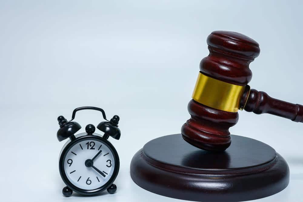 Image is of a gavel beside a clock, concept of the time period a DV charge may remain on a person's record under Florida law.