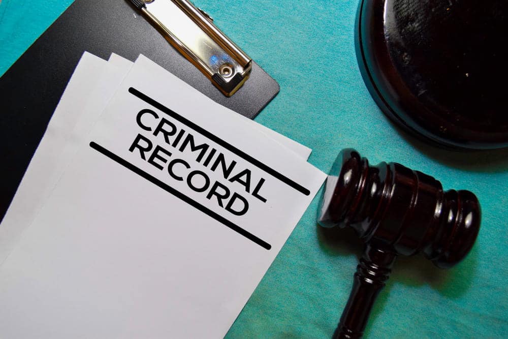 Image is of a criminal record document beside a judge's gavel, concept of how prior convictions affect Ponte Vedra Beach drug charges.