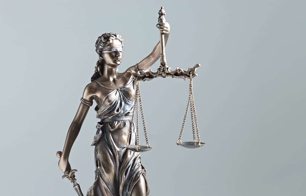 Image is of the Lady Justice statue holding scales, concept of legal standards for search warrants.