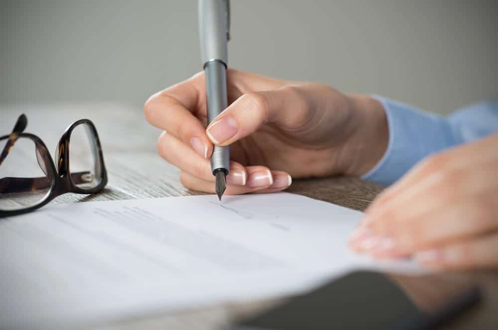 Image is of a person signing legal documents, concept of addressing legal matters when a DUI affect your job opportunities.