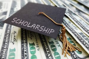 Image is of a scholarship graduation cap over money, concept of scholarship concerns after drug charges