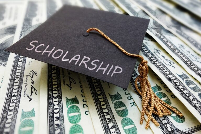 Image is of a scholarship graduation cap over money, concept of scholarship concerns after drug charges