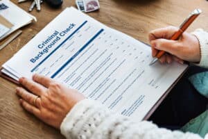 Image is of a person completing a criminal background check form, concept of how DUI charges may appear on background checks.