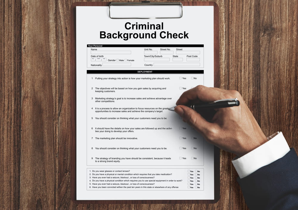 Image is of a criminal background check form on a clipboard, representing how DUI charges may be reviewed during background screening.