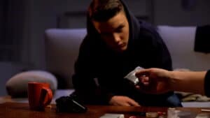 Image is of a young person being shown a small bag of suspected drugs, concept of juvenile drug charges and possession allegations.
